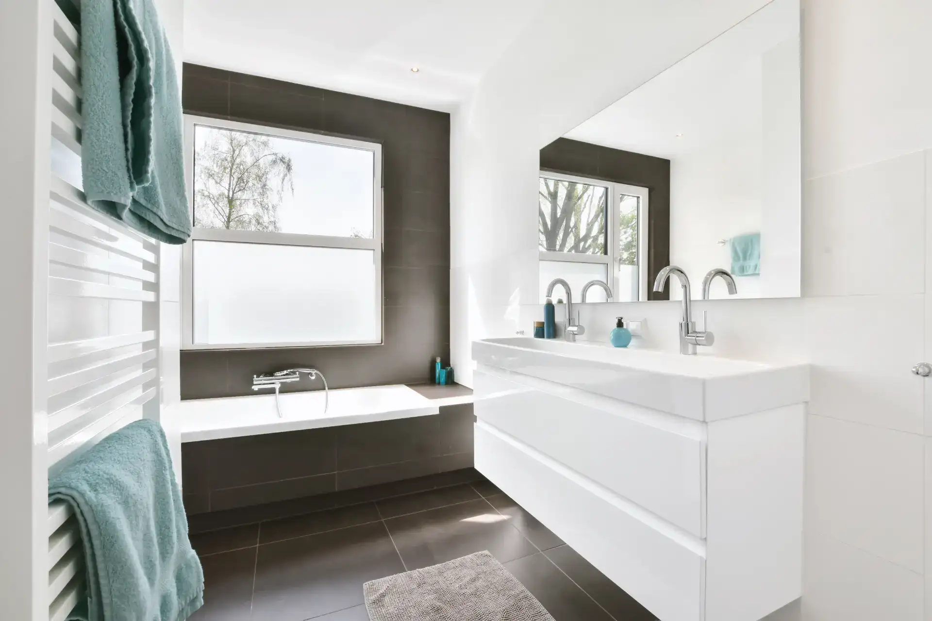 Moderne badeværelse med badekar og stor vaskebord i lyst design.